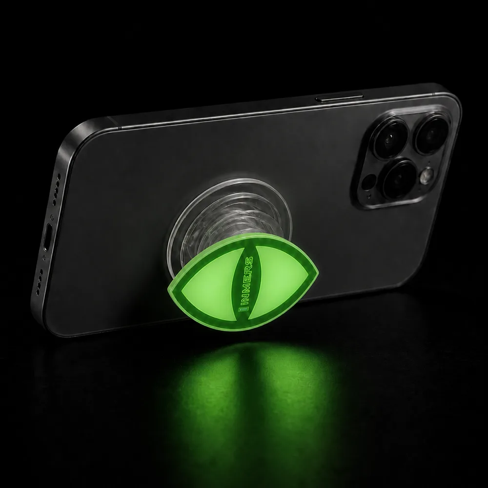 INMERS phone grip glowing green in the dark, propping up a phone