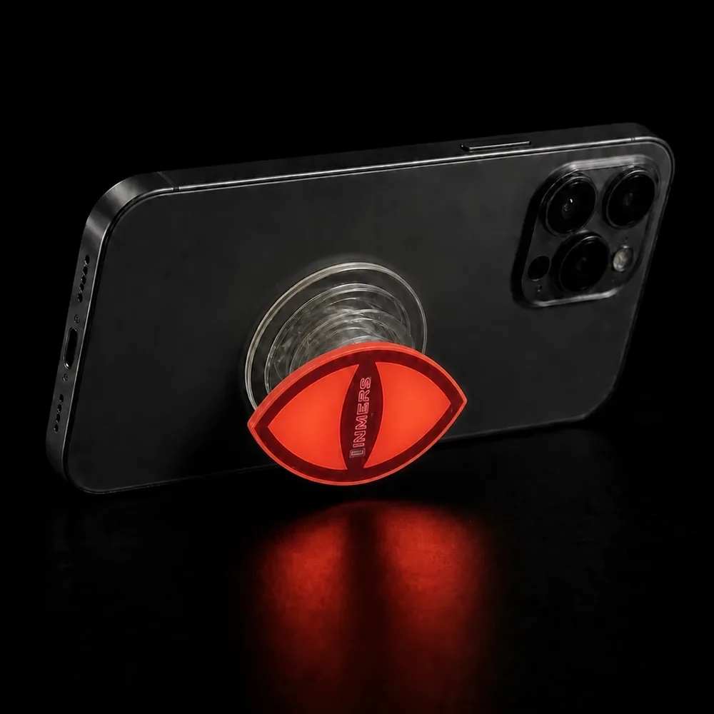 INMERS phone grip glowing red in the dark, propping up a phone
